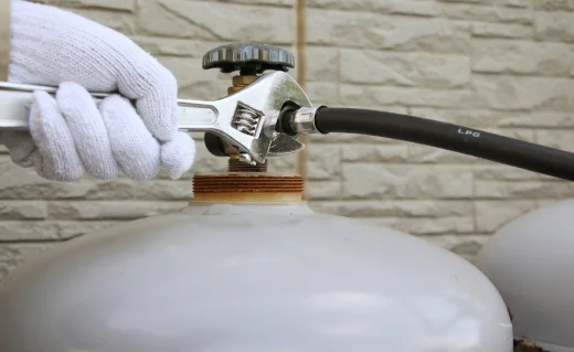 プロパンガスボンベの配管を工具で接続する作業の様子